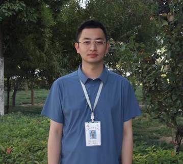 穿着蓝色衣服的男人站在树前 描述已自动生成